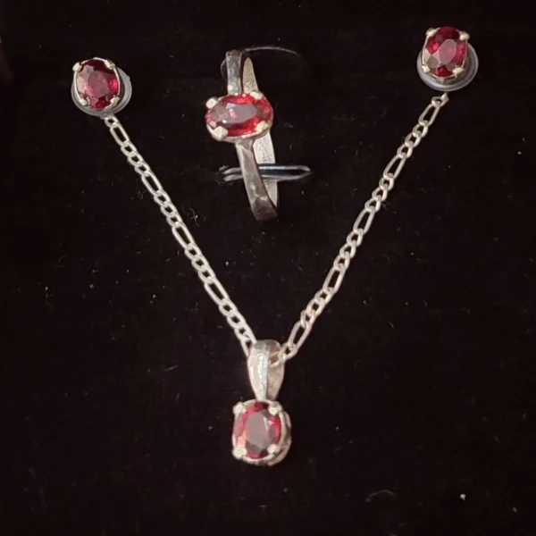 Handcrafted sterling silver jewelry with oval-cut garnet stones in ring, pendant, and earrings.